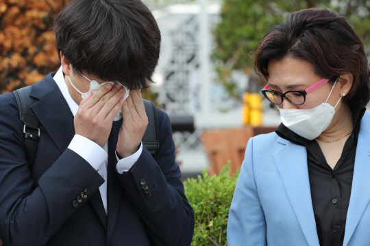 이준석 국민의힘 당대표 후보(왼쪽)가 9일 오전 서울시 용산구 국방부 앞에서 열린 '천안함 참전 장병 및 희생자들의 명예회복을 촉구'하는 피켓 시위에 동참해 발언하던 중 흘린 눈물을 닦고 있다.연합뉴스